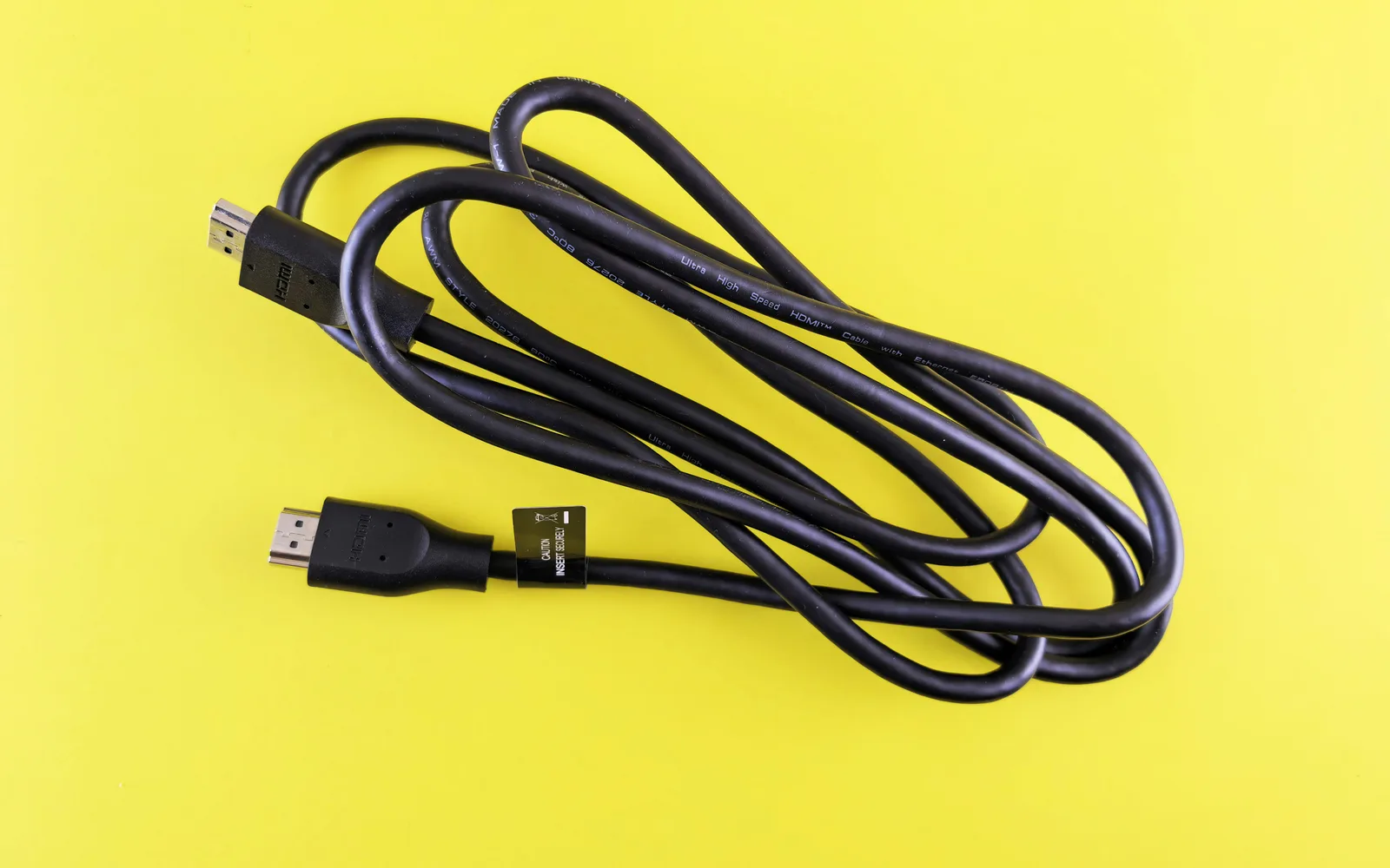 A black USB cable on a bright yellow background